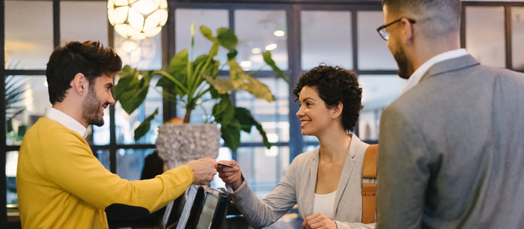 Man and woman smiling at each other at boutique hotel check-in desk.